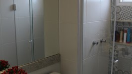 [Banheiro Suíte] - No banheiro da suíte o box recebeu revestimento decorativo e nicho para xampús. O espelho da bancada passa sobre a louça sanitária e ajuda a dar a sensação de um ambiente maior.